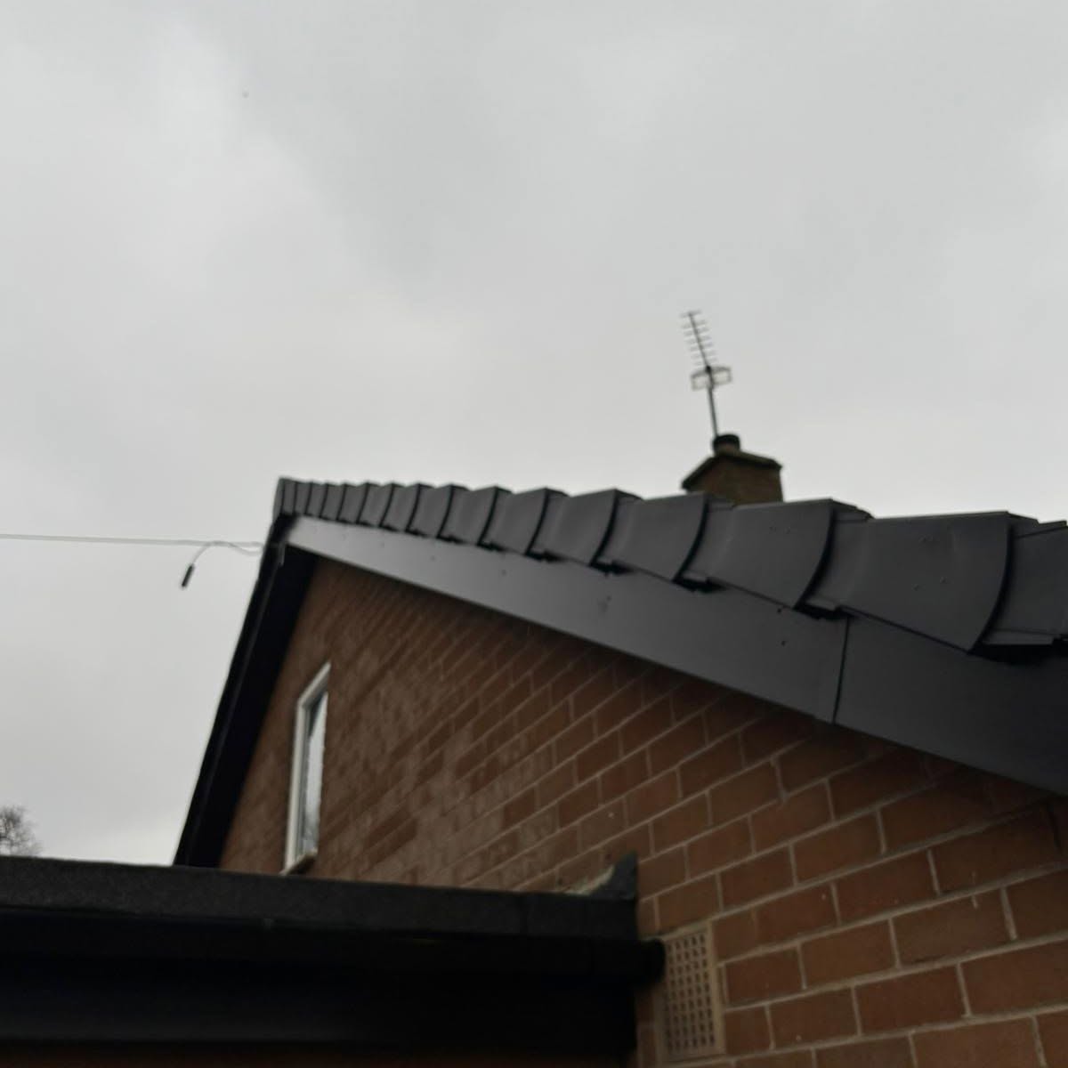 Black fascias and dry verge along a brick gable roofline