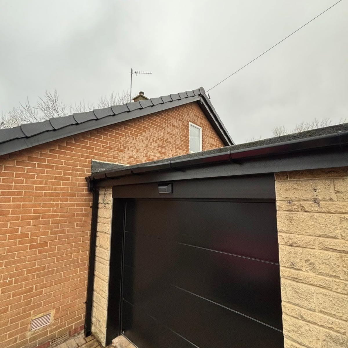 Black fascias and guttering above a garage with a black garage door