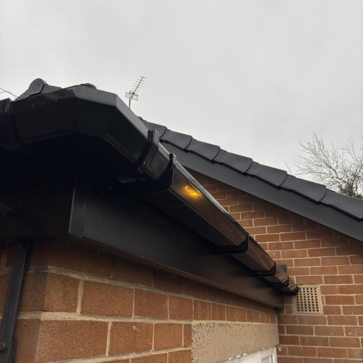 Black fascias, soffits and guttering corner detail on brickwork