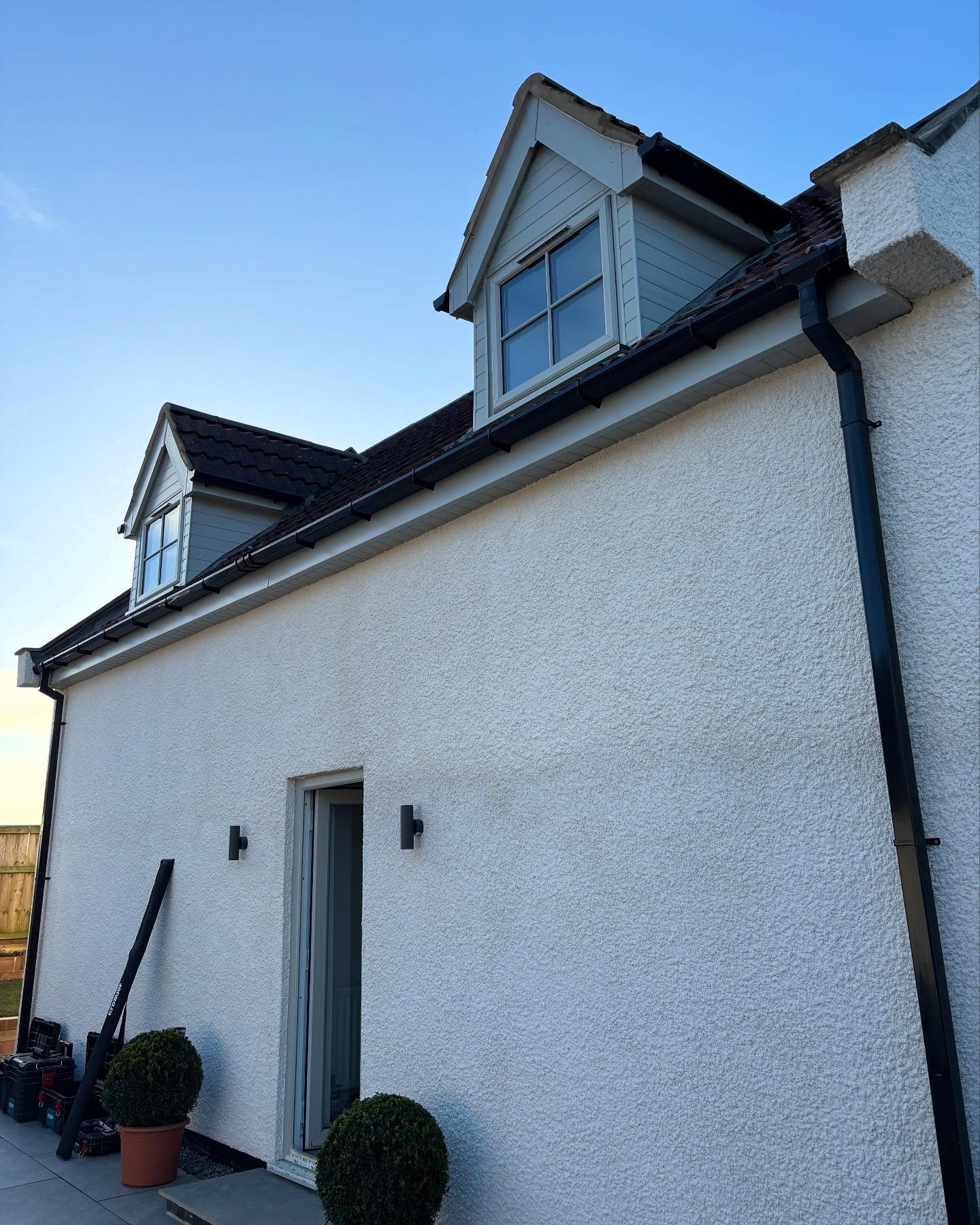 White fascias and soffits with black guttering on a rendered house